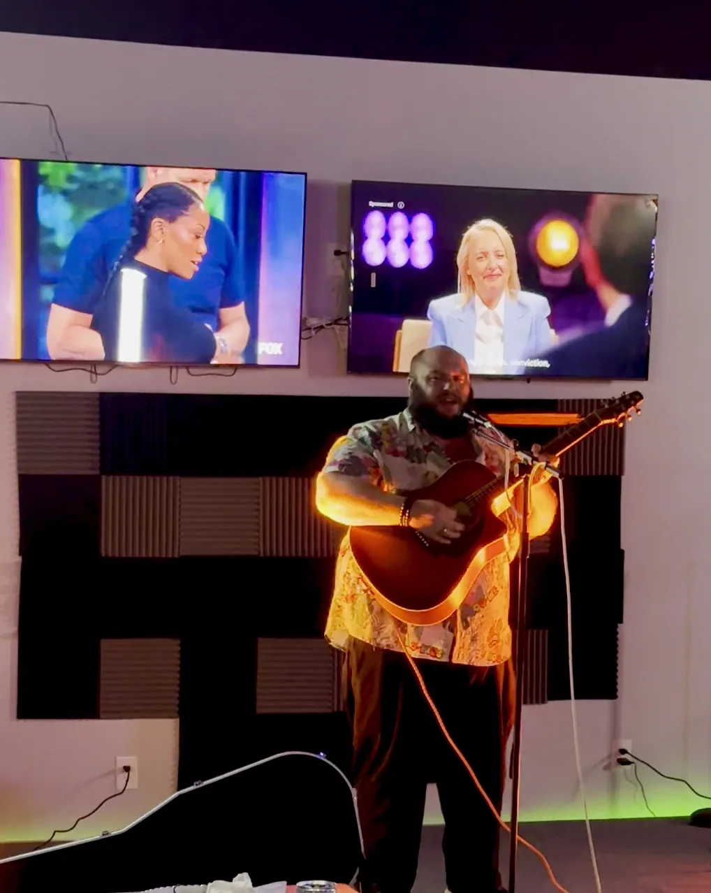 A singer with an acoustic guitar playing on The 183's small stage under warm lights
