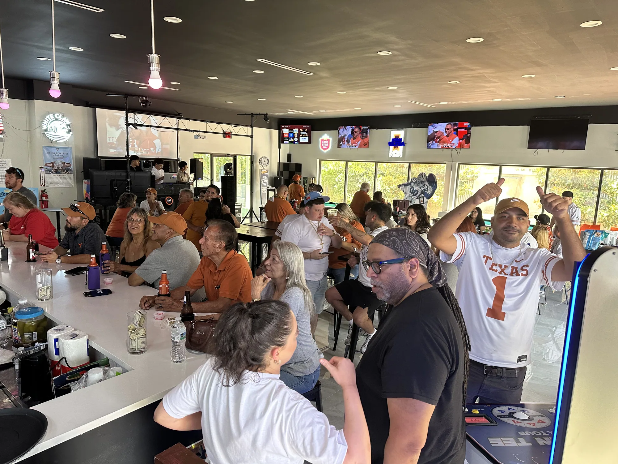 A packed bar of fans in burnt orange cheering during a Texas game