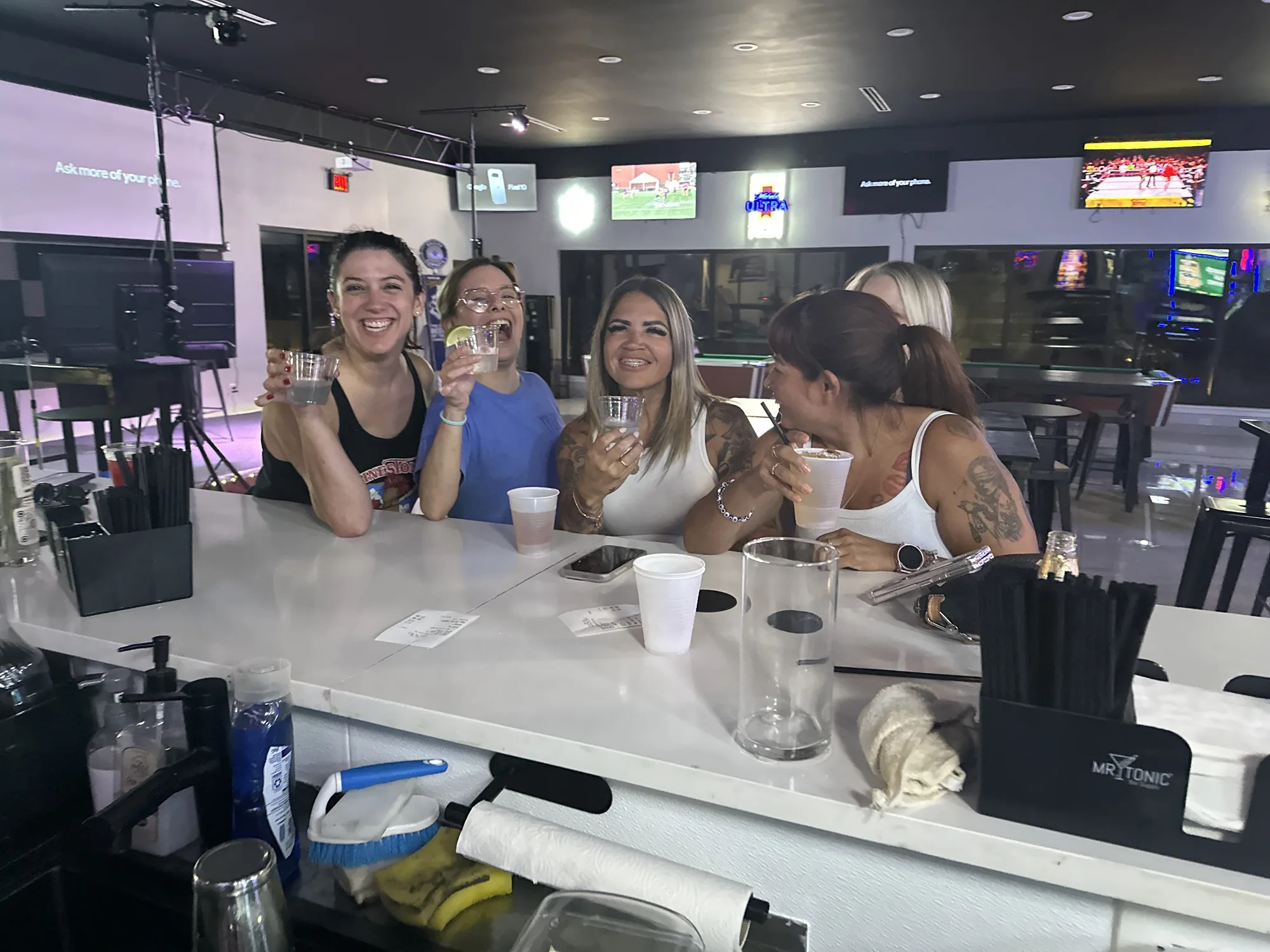 Four friends raising their drinks for a toast at the bar